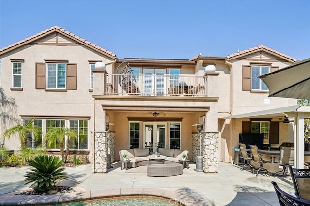 back of property featuring french doors, a balcony, ceiling fan, an outdoor living space, and a patio