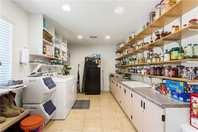 clothes washing area with washing machine and clothes dryer, light tile patterned flooring, and a healthy amount of sunlight