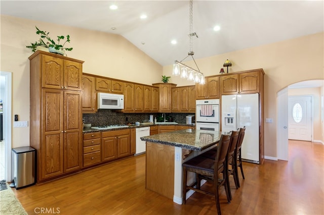 kitchen with backsplash, white appliances, a kitchen island, and dark hardwood / wood-style flooring