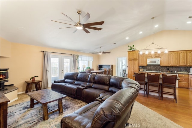 living room with light wood-type flooring, ceiling fan, french doors, and high vaulted ceiling