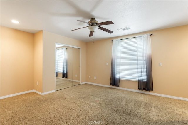 spare room featuring light carpet, ceiling fan, and a healthy amount of sunlight