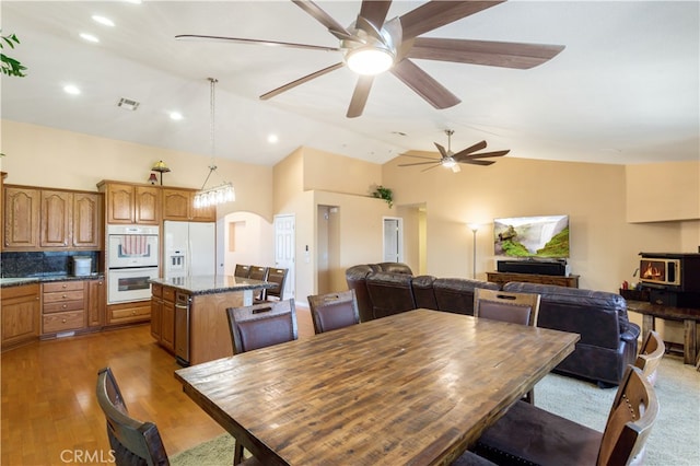 dining area featuring light hardwood / wood-style floors, ceiling fan, and high vaulted ceiling