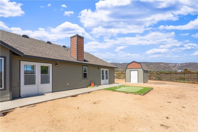 rear view of house featuring a patio, a storage shed, and a mountain view