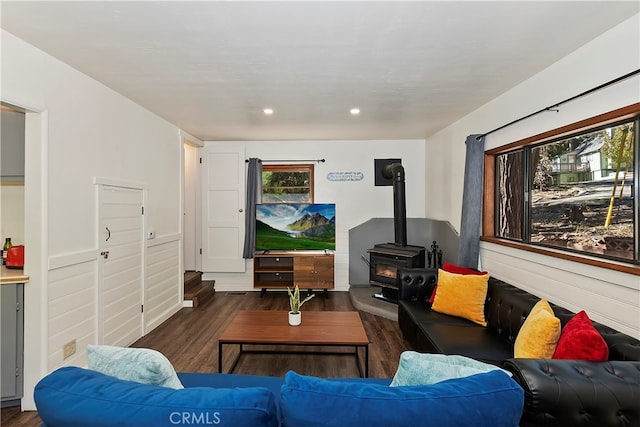 living room featuring dark wood-type flooring, a wood stove, and a healthy amount of sunlight