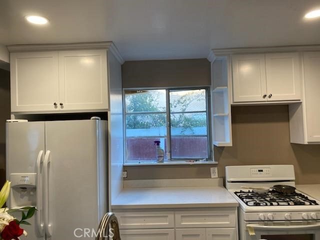 kitchen with white appliances, white cabinets, and light countertops