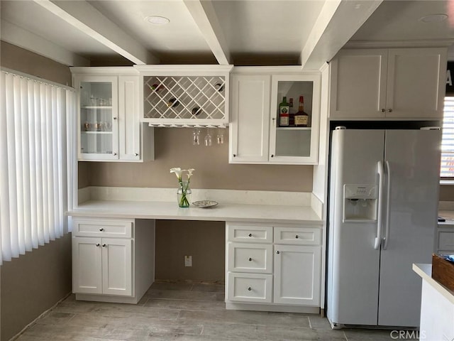 kitchen featuring white refrigerator with ice dispenser, wood tiled floor, glass insert cabinets, and white cabinets