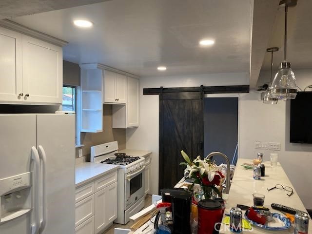 kitchen featuring recessed lighting, light countertops, a barn door, white cabinetry, and white appliances