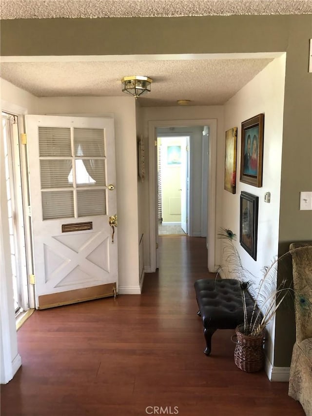 doorway featuring a healthy amount of sunlight, a textured ceiling, baseboards, and wood finished floors