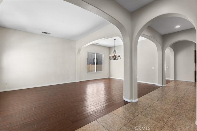 empty room featuring dark hardwood / wood-style flooring and a chandelier