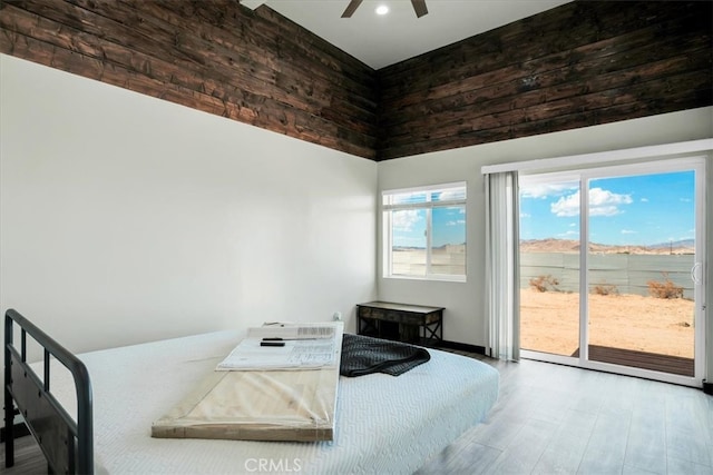 bedroom featuring a towering ceiling, ceiling fan, access to exterior, and hardwood / wood-style floors