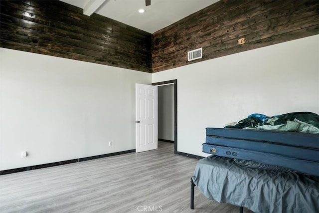 bedroom with wood-type flooring, beam ceiling, and a high ceiling