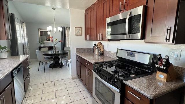 kitchen featuring light tile patterned floors, appliances with stainless steel finishes, an inviting chandelier, hanging light fixtures, and stone countertops