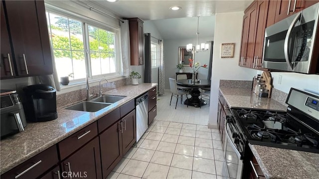 kitchen with decorative light fixtures, sink, a notable chandelier, light stone counters, and stainless steel appliances