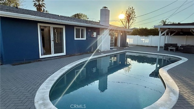 pool at dusk featuring a patio area