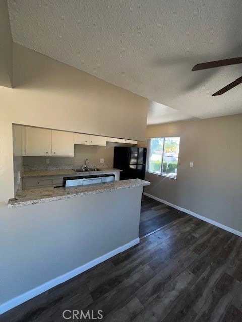 kitchen with a textured ceiling, kitchen peninsula, white cabinetry, and dark wood-type flooring