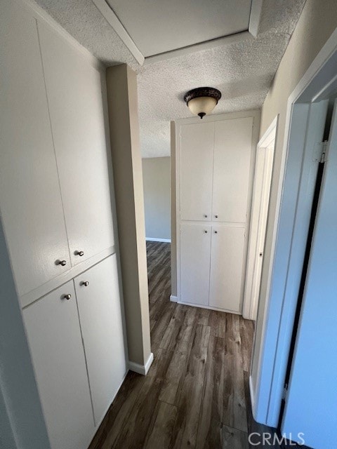 hall featuring a textured ceiling and dark hardwood / wood-style floors