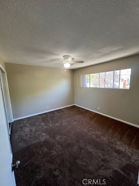 carpeted empty room featuring a textured ceiling, ceiling fan, and plenty of natural light