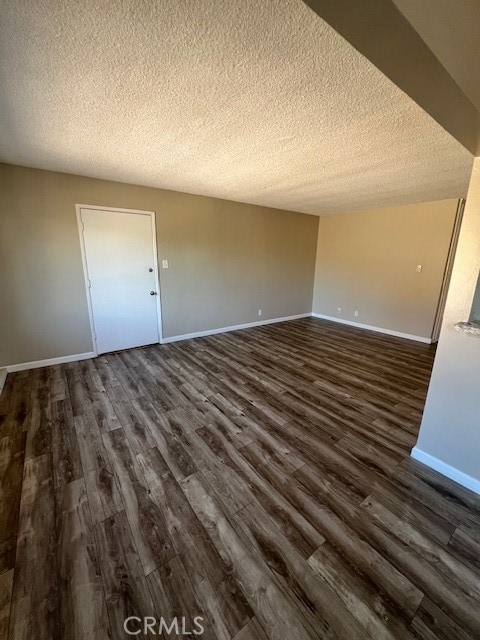 spare room with a textured ceiling and dark hardwood / wood-style flooring