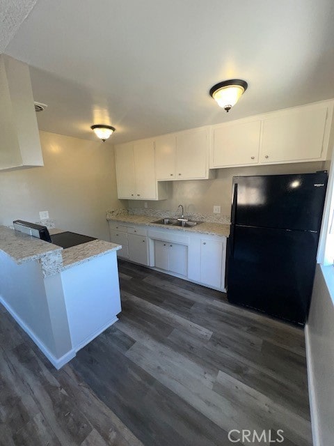 kitchen with dark hardwood / wood-style floors, black fridge, sink, and white cabinets