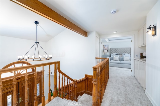 hall with beamed ceiling, light carpet, and a chandelier