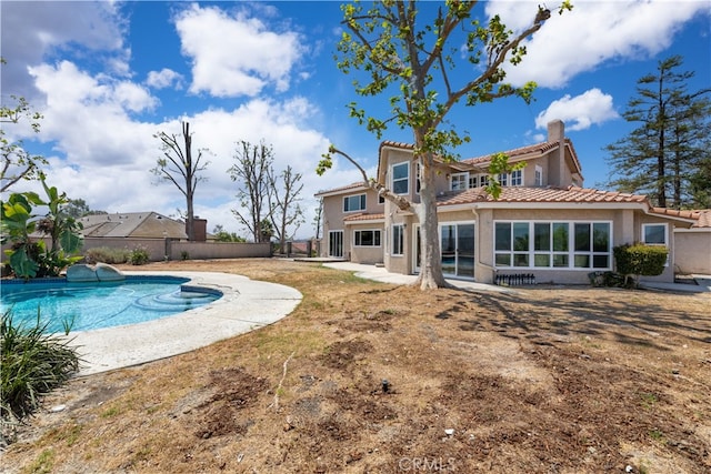 rear view of property featuring a fenced in pool and a patio area