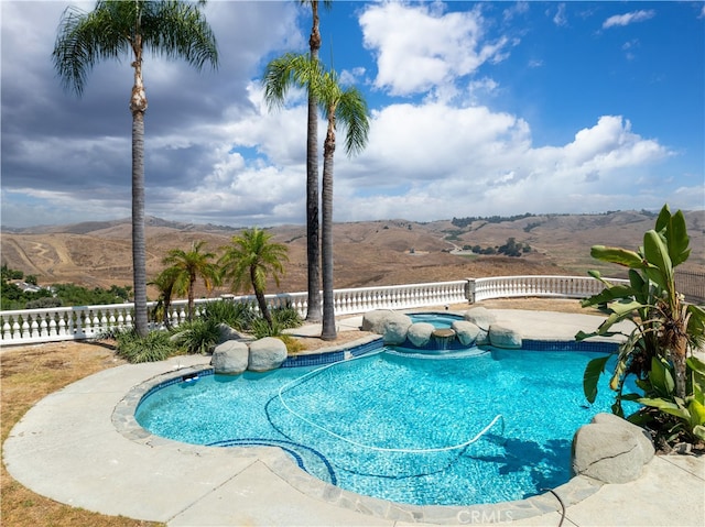 view of swimming pool featuring a mountain view, an in ground hot tub, and a patio area