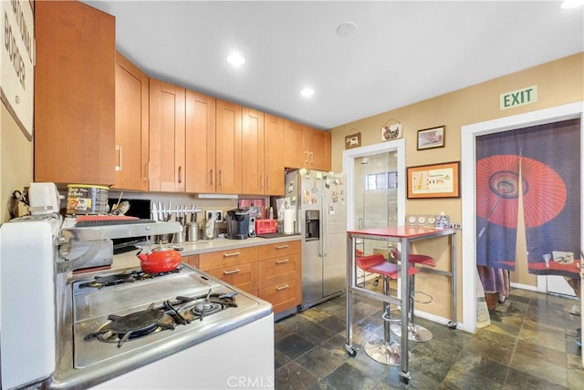 kitchen featuring stainless steel fridge with ice dispenser and white gas range oven