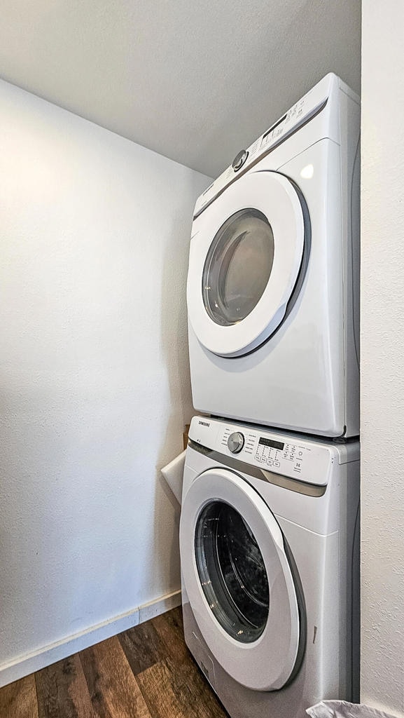 washroom with stacked washer / dryer and dark hardwood / wood-style flooring