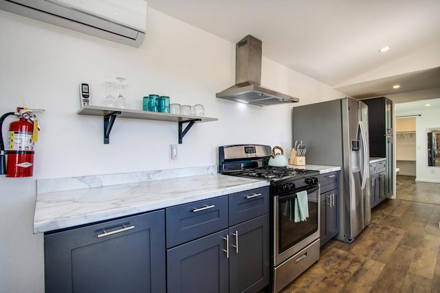 kitchen with dark wood-type flooring, appliances with stainless steel finishes, exhaust hood, a wall mounted air conditioner, and light stone countertops