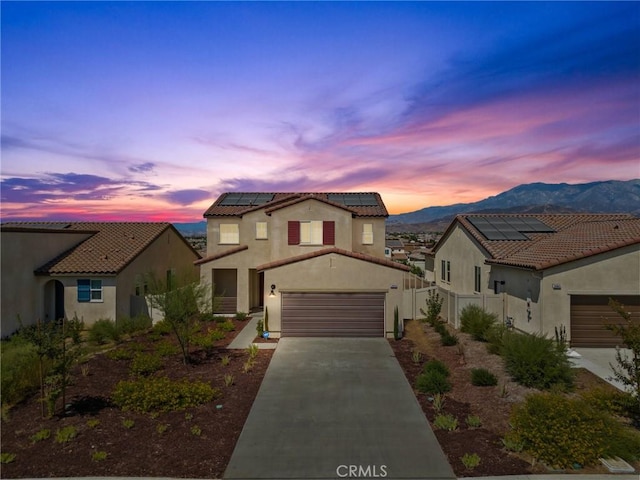 mediterranean / spanish home featuring a mountain view, a garage, and solar panels