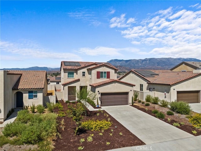 mediterranean / spanish home featuring a mountain view, a garage, and solar panels