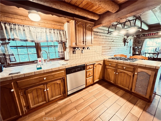 kitchen with appliances with stainless steel finishes, a healthy amount of sunlight, light hardwood / wood-style floors, and tile countertops