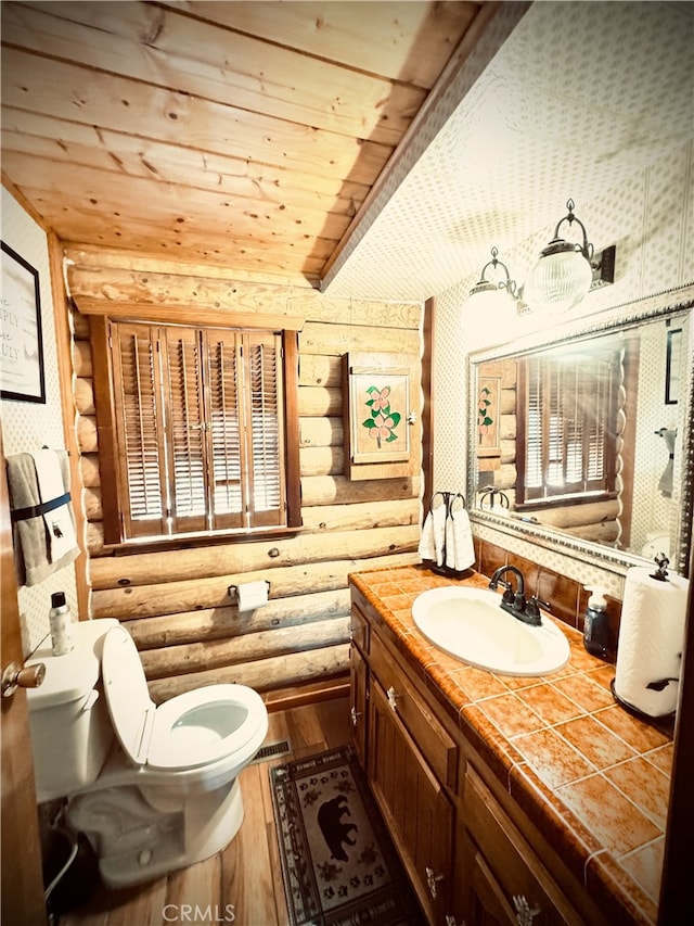 bathroom featuring wood-type flooring, log walls, wooden ceiling, vanity, and toilet