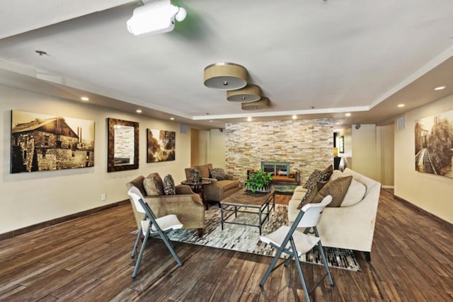 cinema room with a fireplace, dark hardwood / wood-style floors, and a tray ceiling