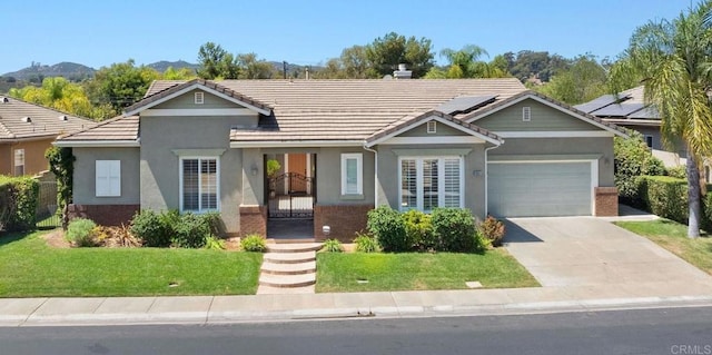 ranch-style home featuring a mountain view, a garage, solar panels, and a front lawn