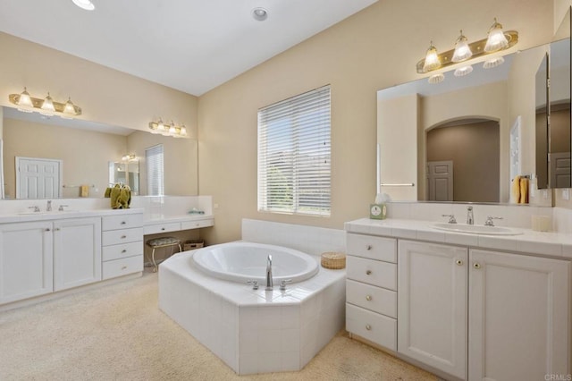 full bathroom with two vanities, a sink, and a bath