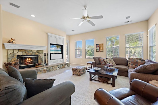 living area with ceiling fan, a fireplace, visible vents, and light colored carpet