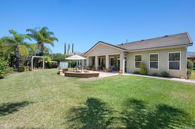 rear view of property with a lawn, a patio area, and stucco siding