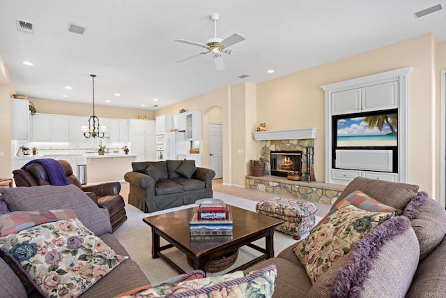 living area with ceiling fan with notable chandelier, a fireplace, visible vents, and recessed lighting