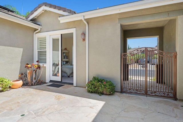 doorway to property with a patio area, a gate, and stucco siding