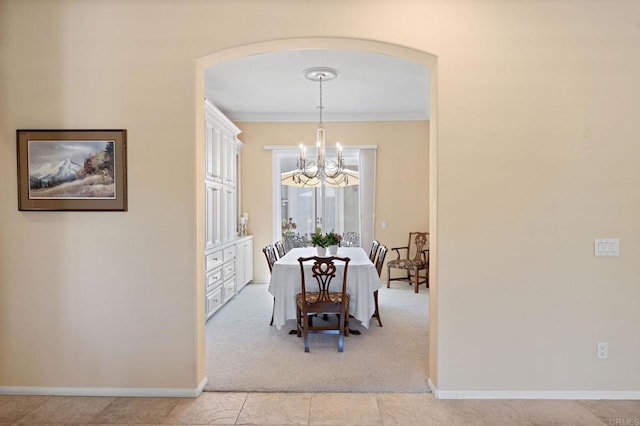 dining room featuring baseboards, arched walkways, a notable chandelier, and ornamental molding