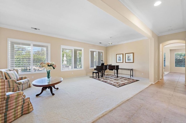 interior space featuring arched walkways, light carpet, a ceiling fan, visible vents, and crown molding