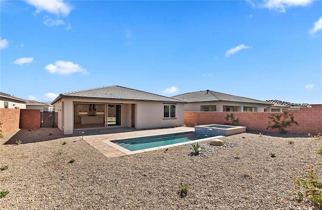 back of house featuring an in ground hot tub and a patio area