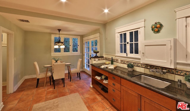 kitchen featuring sink, dark stone countertops, a chandelier, decorative light fixtures, and light tile patterned floors