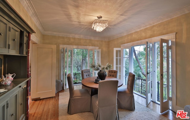 dining space featuring crown molding, light hardwood / wood-style flooring, a healthy amount of sunlight, and a notable chandelier