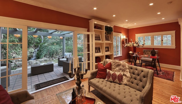 living room featuring wood-type flooring, ornamental molding, and a wealth of natural light