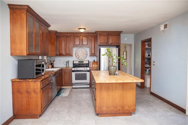 kitchen with wood counters, sink, a center island, and appliances with stainless steel finishes