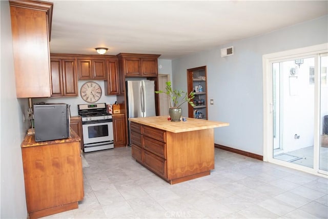 kitchen featuring wood counters, a kitchen island, stainless steel refrigerator, and white gas stove