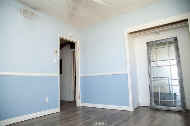 empty room with dark hardwood / wood-style flooring and a textured ceiling