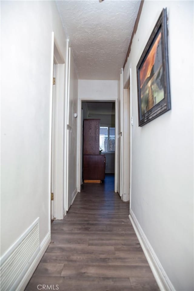 hallway featuring dark hardwood / wood-style flooring and a textured ceiling